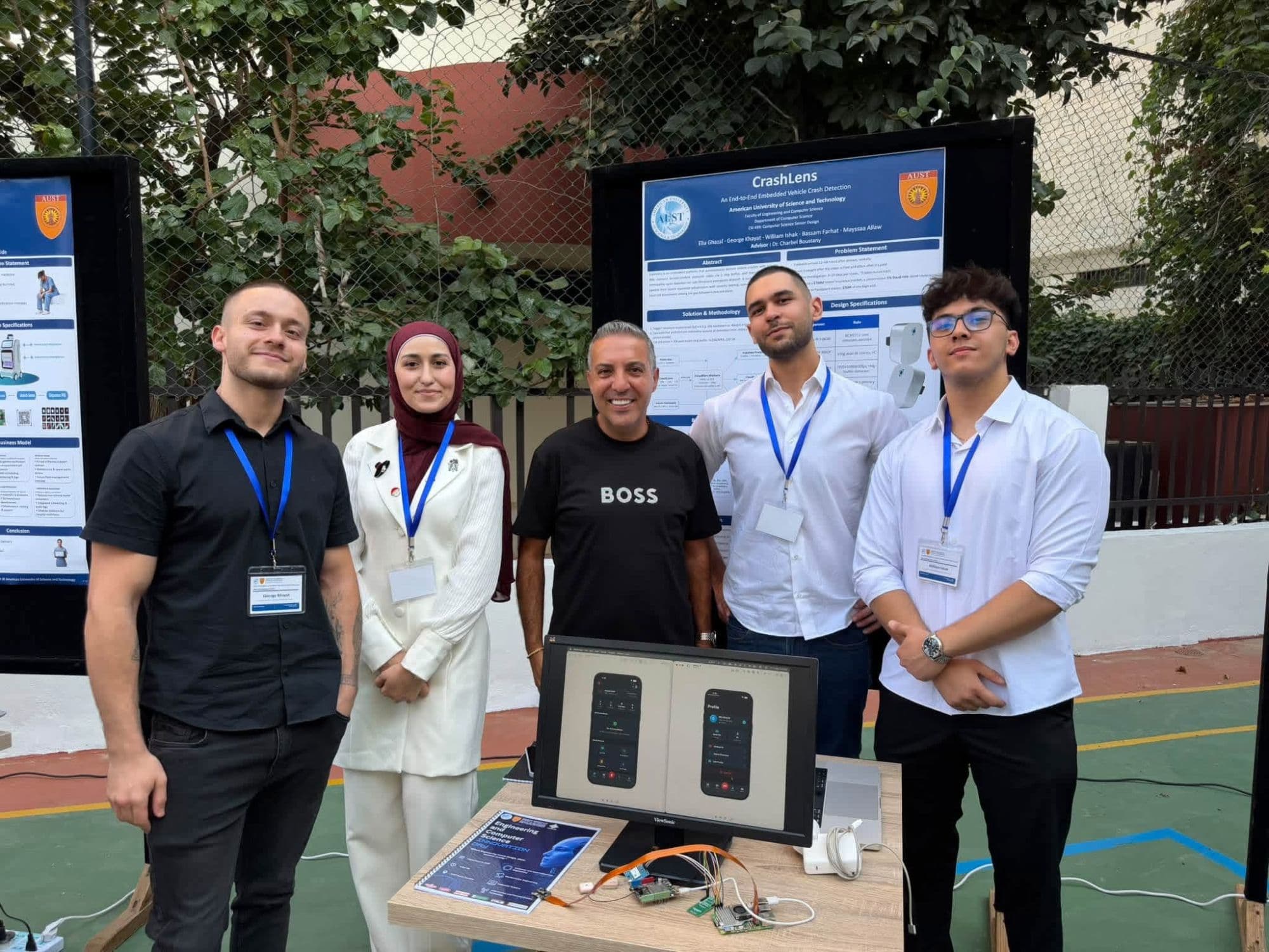 Elia Ghazal presenting CrashLens to a visitor at the AUST Engineering and Computer Science Expo 2026, beside the team's poster and hardware